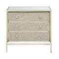 Commode en bois à trois tiroirs avec finition capitonnée, plateau miroir et poignées anneaux.