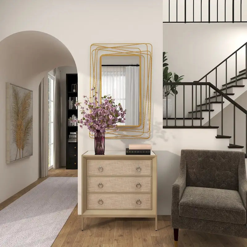 Commode en bois à trois tiroirs avec finition capitonnée, plateau miroir et poignées anneaux.