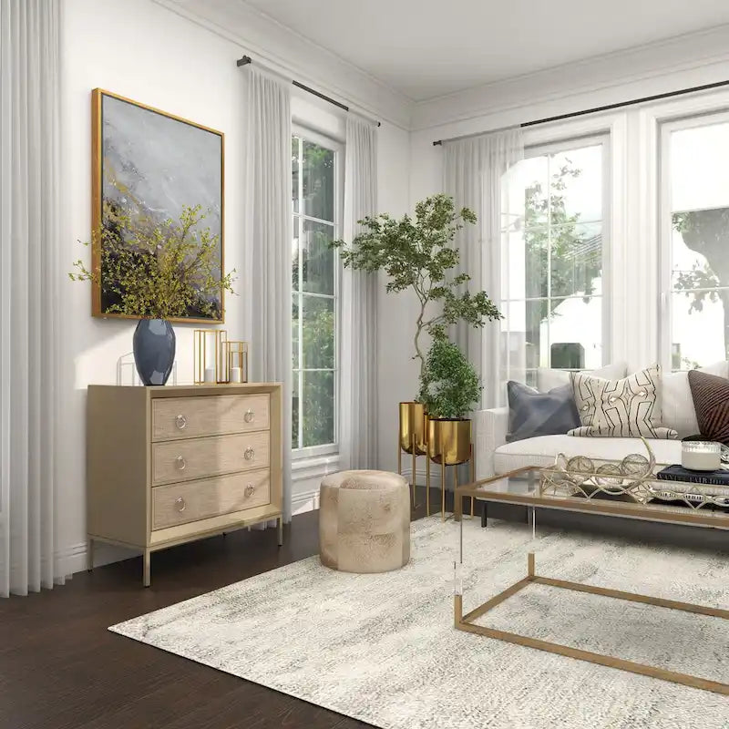 Commode en bois à trois tiroirs avec finition capitonnée, plateau miroir et poignées anneaux.