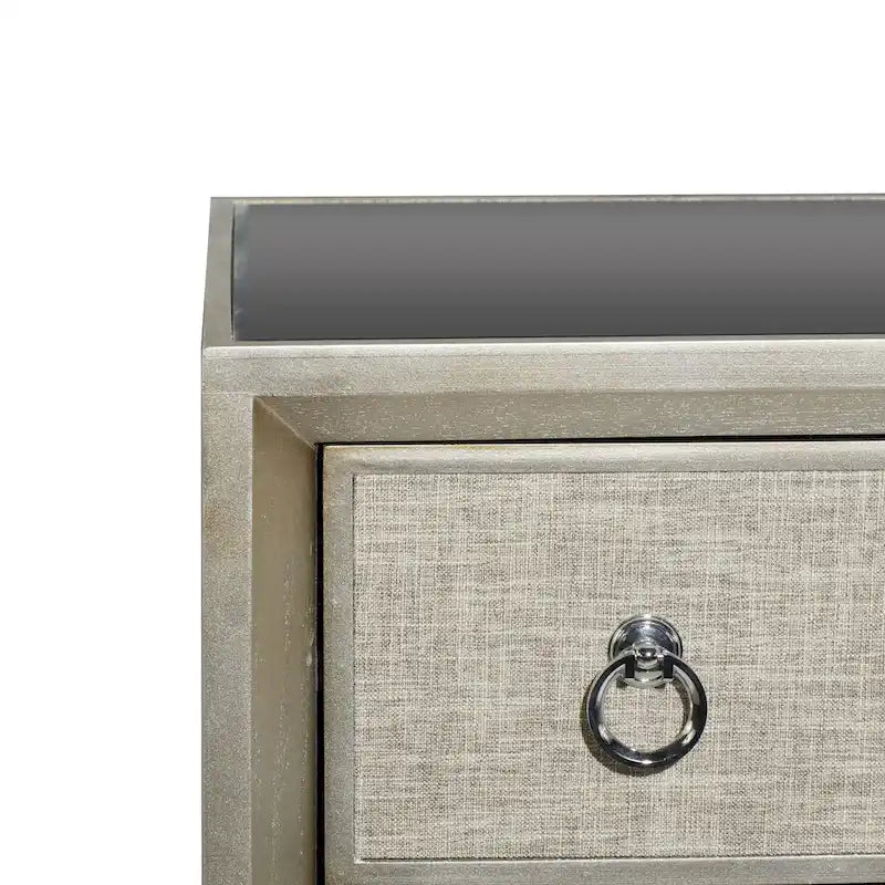 Commode en bois à trois tiroirs avec finition capitonnée, plateau miroir et poignées anneaux.