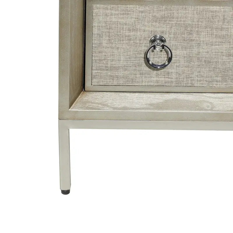 Commode en bois à trois tiroirs avec finition capitonnée, plateau miroir et poignées anneaux.