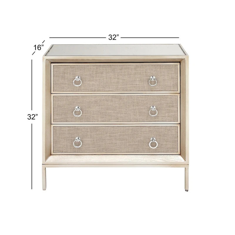 Commode en bois à trois tiroirs avec finition capitonnée, plateau miroir et poignées anneaux.